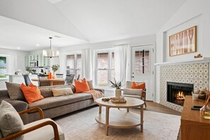 A modern living room with a sofa, chairs, a fireplace, and a dining area with a table and chairs.
