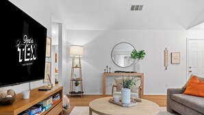 A modern living room with a flat-screen TV, wooden furniture, a round coffee table, and a fireplace.