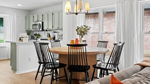 A modern kitchen with white cabinets, a central island, and a dining area with black chairs.