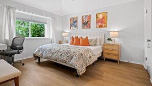 A bedroom with a bed, bedside tables, a chair, a desk, and a window with curtains.