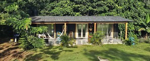 Une maison moderne dotée d’une grande façade vitrée, d’un porche en bois et d’un jardin bien entretenu.