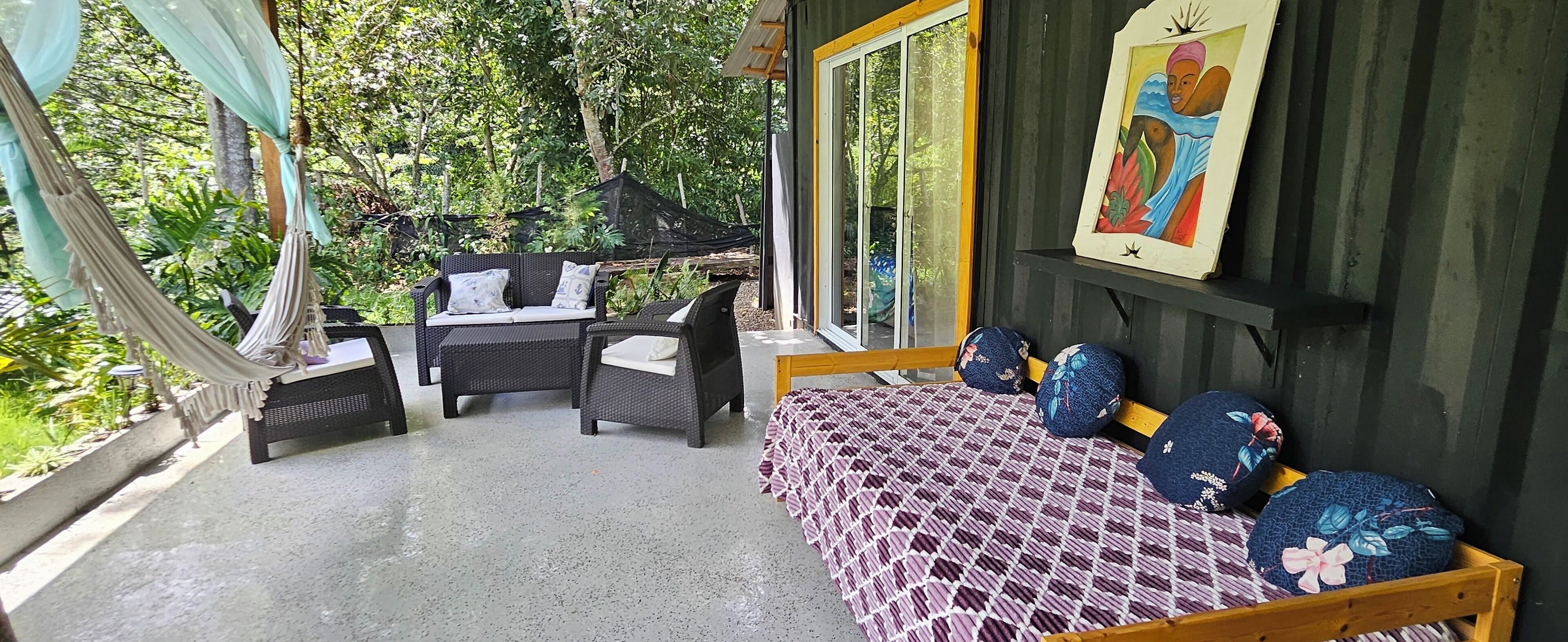 Ein Zimmer mit einem Bett, einem Sofa und einem Tisch. Ein Fenster bietet Blick auf Bäume.