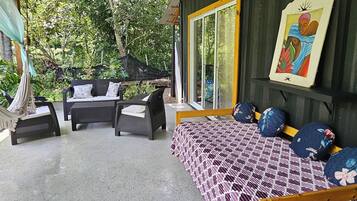 Ein Zimmer mit einem Bett, einem Sofa und einem Tisch. Ein Fenster bietet Blick auf Bäume.