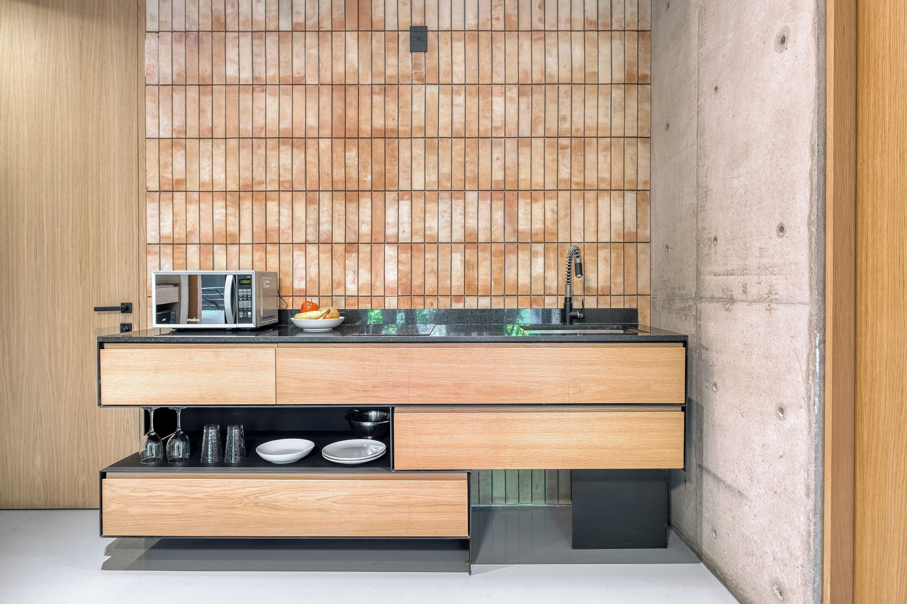 Een moderne keuken met een houten aanrechtblad, ingebouwde apparatuur en een betegelde spatwand.