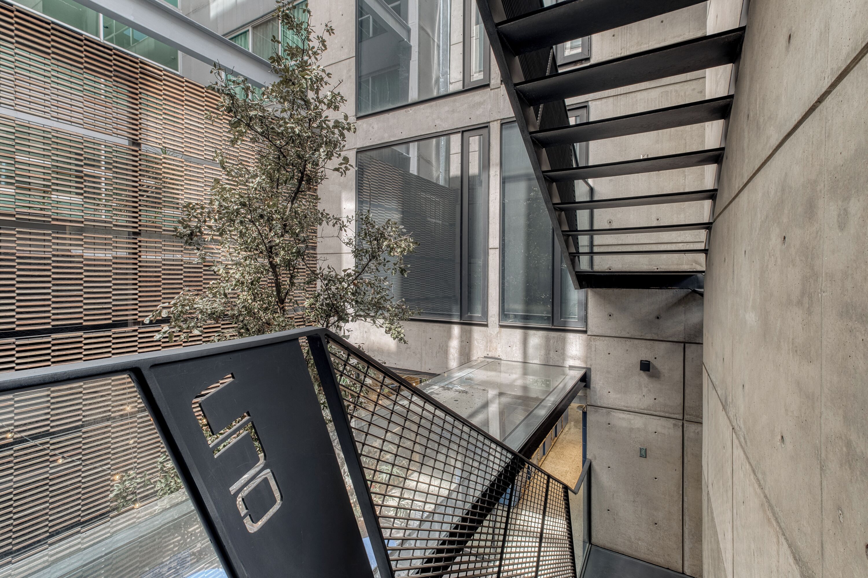 A modern building with a concrete facade, large windows, and a metal staircase.
