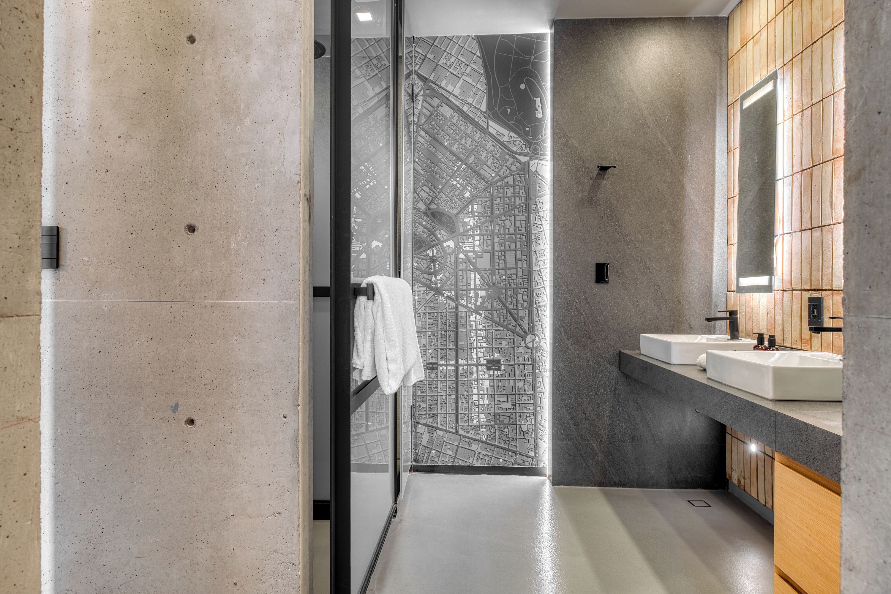 A modern bathroom with a large mirror, two sinks, and a towel rack.