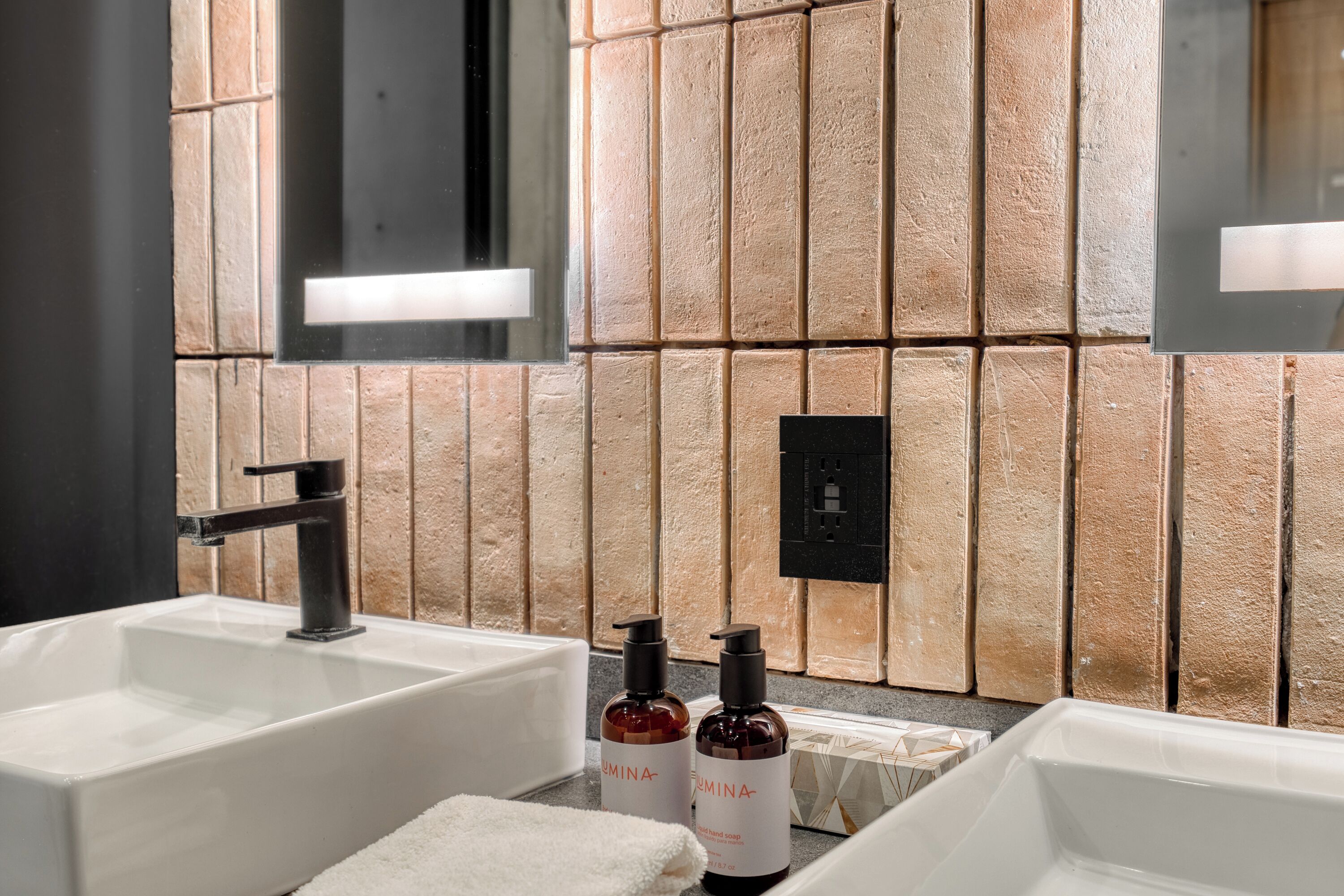 A bathroom with two sinks, a mirror, and a textured wall.