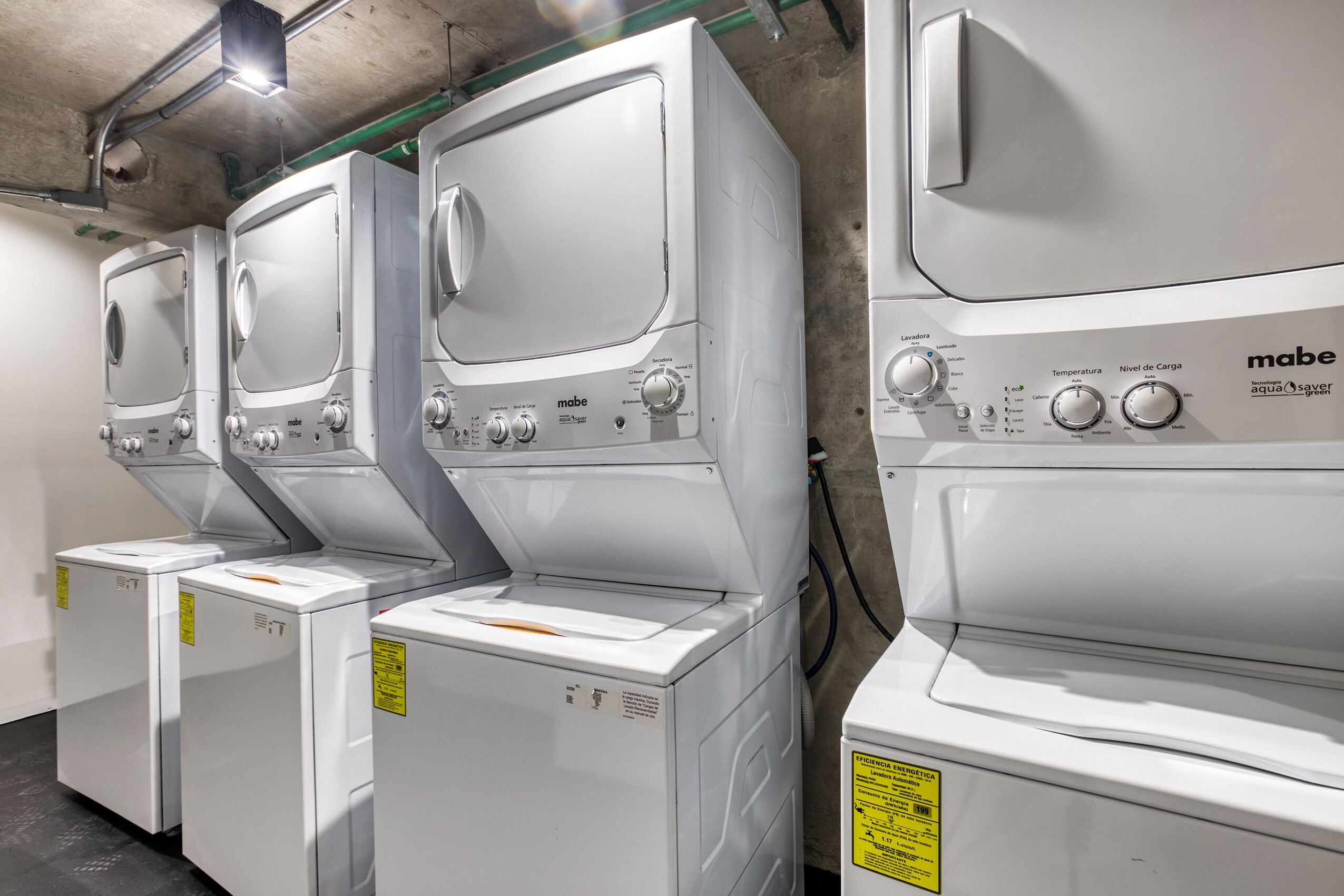 Une rangée de machines à laver Mabe blanches dans un environnement commercial.