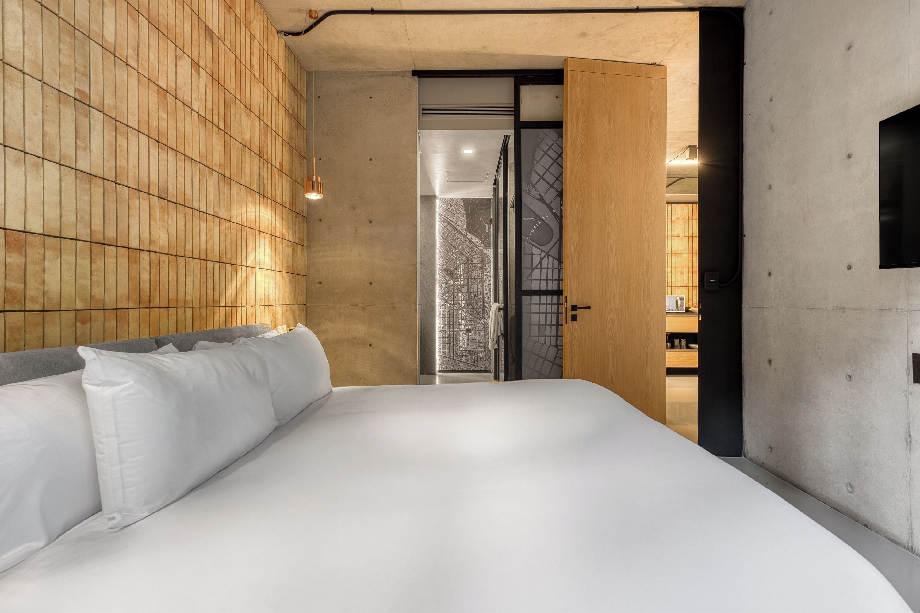 A modern bedroom with a large bed, wooden panel walls, and a view of a cityscape through a glass door.