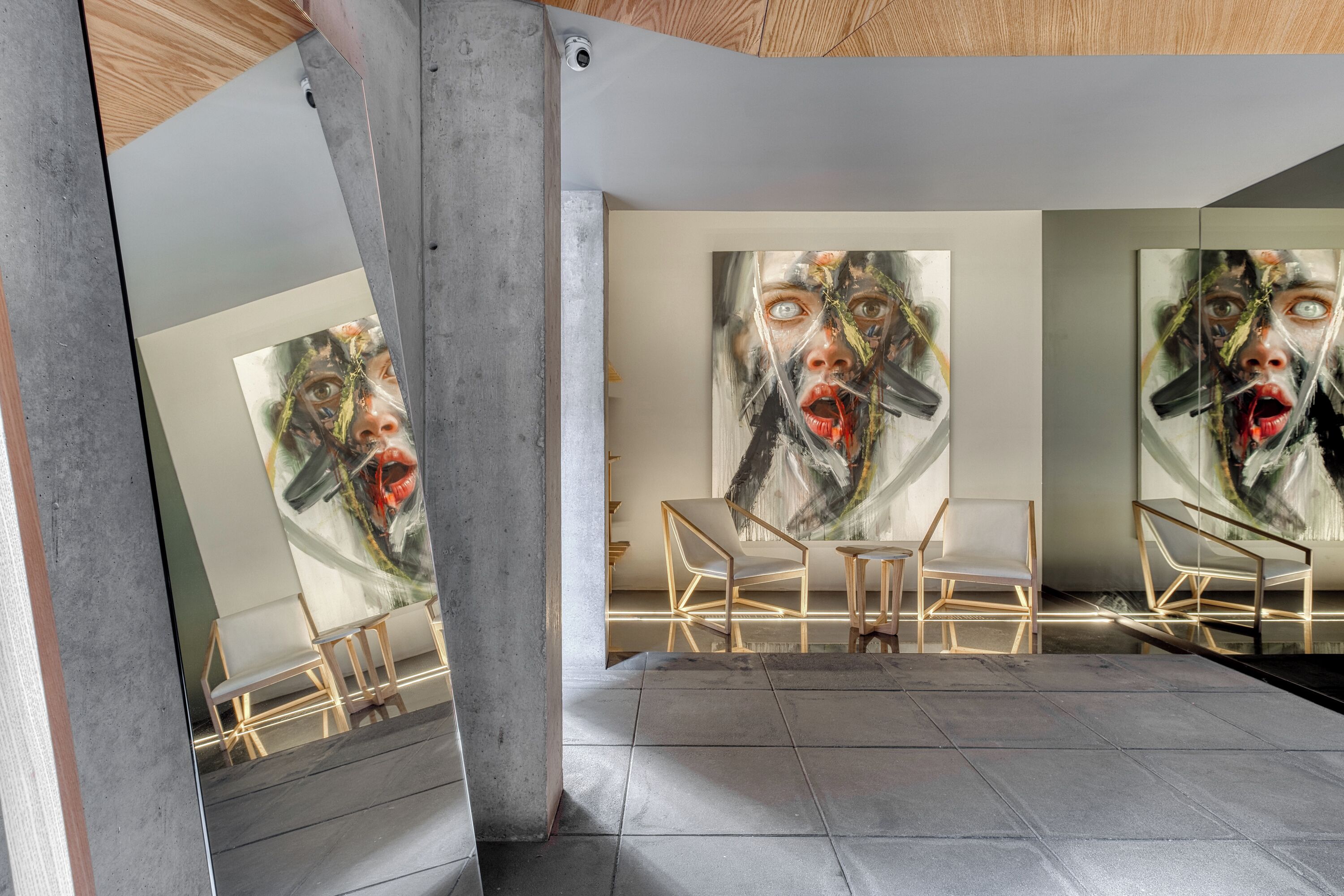 Ein modernes Interieur mit einem großen, abstrakten Gemälde, einer Sitzecke mit Sesseln und einem spiegelnden Boden.