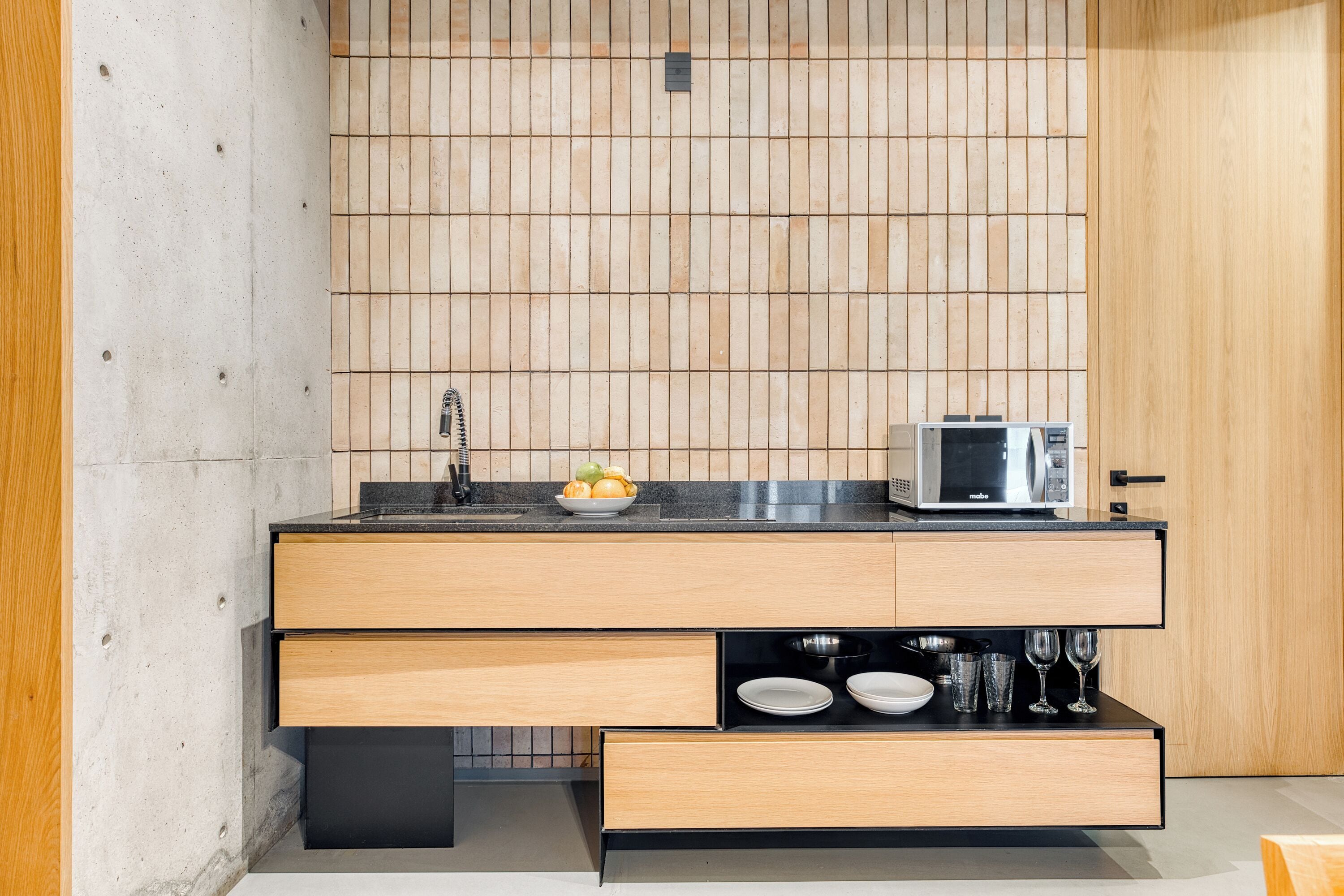 A modern kitchen with a wooden countertop, a microwave, and a fruit bowl.