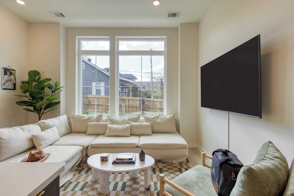 A living room with a sectional sofa, a coffee table, and a TV mounted on the wall. - Lischey by Avantstay Modern 4bdr w/ Covered Patio Newly Built Nashville Home (Nashville)
