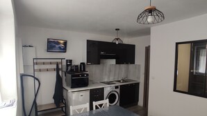 Une cuisine compacte comprenant une table et des chaises, un lave-linge et un petit réfrigérateur.