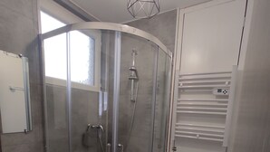 Une salle de bain moderne avec une douche à parois de verre, un lavabo blanc et des toilettes.