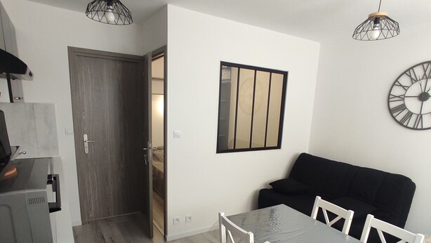 Une cuisine moderne avec un coin repas, dotée d’un plancher en bois, de murs blancs et de meubles contemporains.