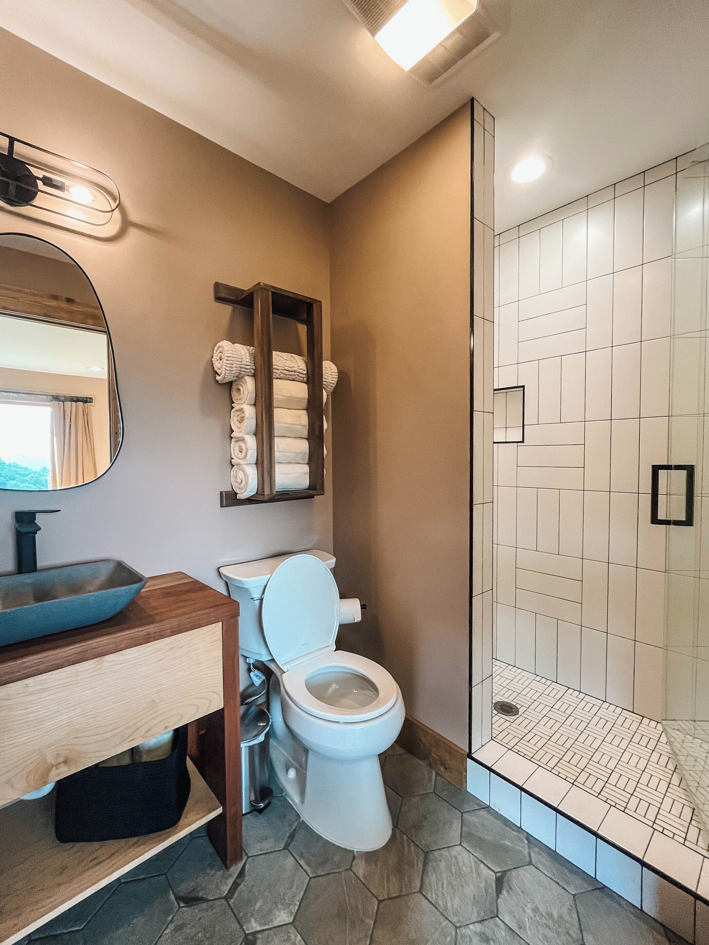 Een badkamer met een moderne wastafel, toilet en een douchecabine van glas.