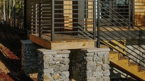 Een moderne houten cabin met een stenen fundering, grote ramen en een metalen trap.