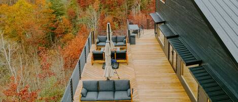 Eine Terrasse mit Sitzgelegenheiten im Freien und einem Feuerkorb, umgeben von Herbstlaub.
