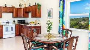Una cocina con armarios de madera, una estufa y un comedor con una mesa redonda y sillas.