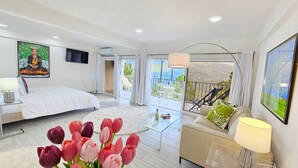 Ein modernes Schlafzimmer mit einem großen Bett, einem Balkon mit Blick und einem Bild an der Wand.