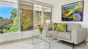 Ein modernes Wohnzimmer mit einer Couch, einem Glastisch und einem Gemälde.