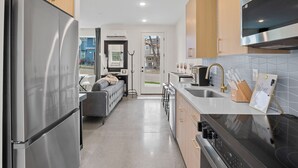 A modern kitchen with stainless steel appliances, wooden cabinets, and a grey tiled backsplash. - Back 2 The Future! - 4 Min. from Downtown Knox (Knoxville)