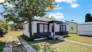 Una casa mobile a un piano con un piccolo portico, una porta ben visibile e un cortile recintato.