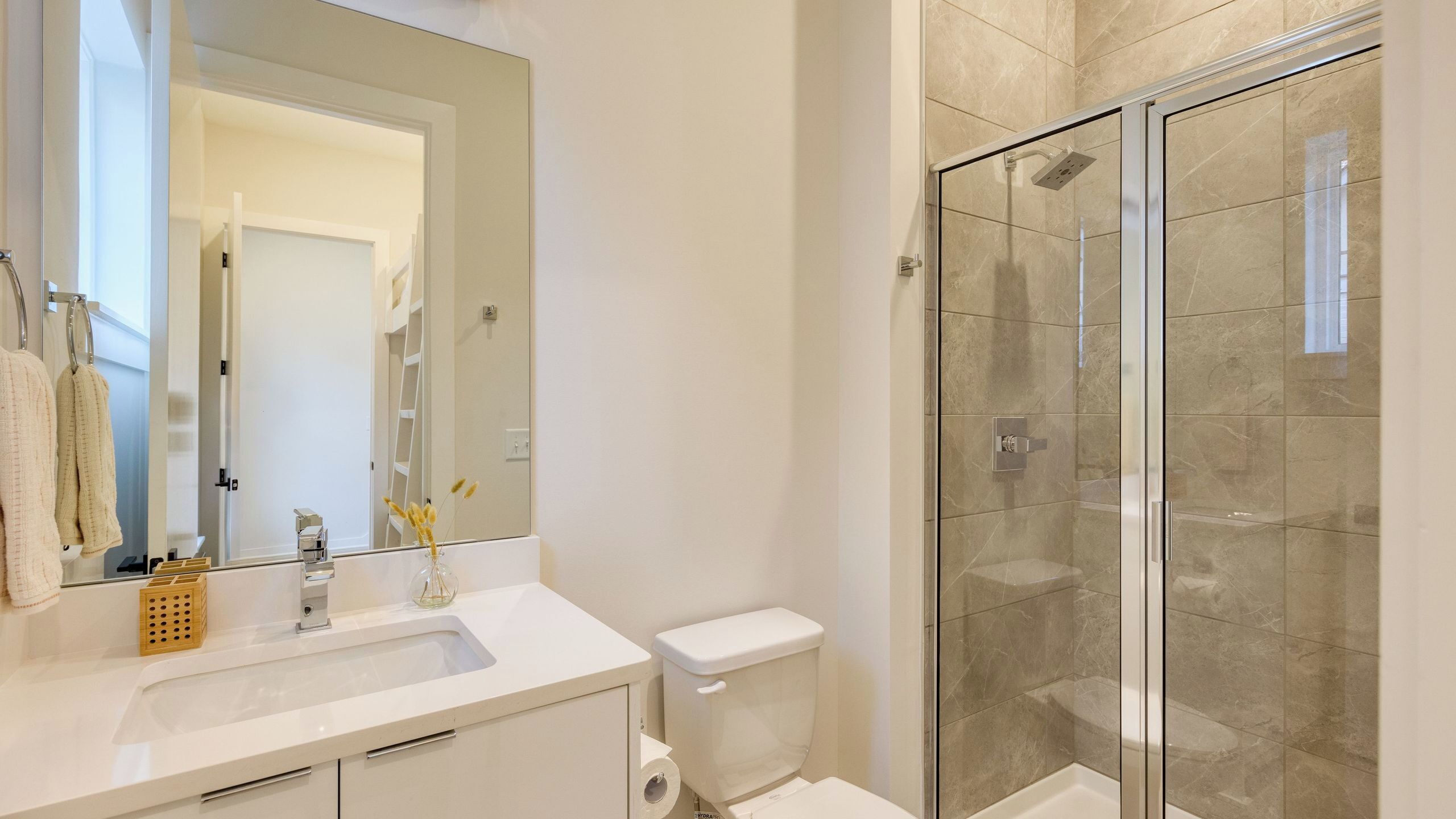 A bathroom with a glass shower enclosure, a white sink, and a toilet.