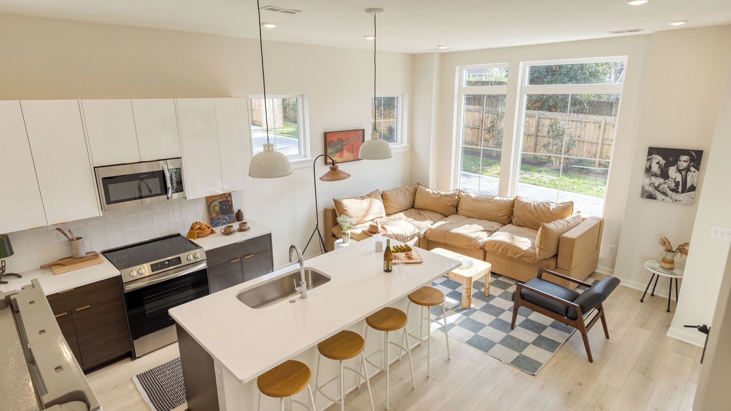 A modern kitchen with a central island, bar stools, a sofa, and a dining area.