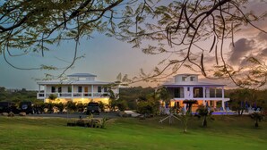 A two-story building with a balcony, surrounded by greenery and parked vehicles. - Club Vieques - Adults Only Resort - LGBT Friendly (Vieques)