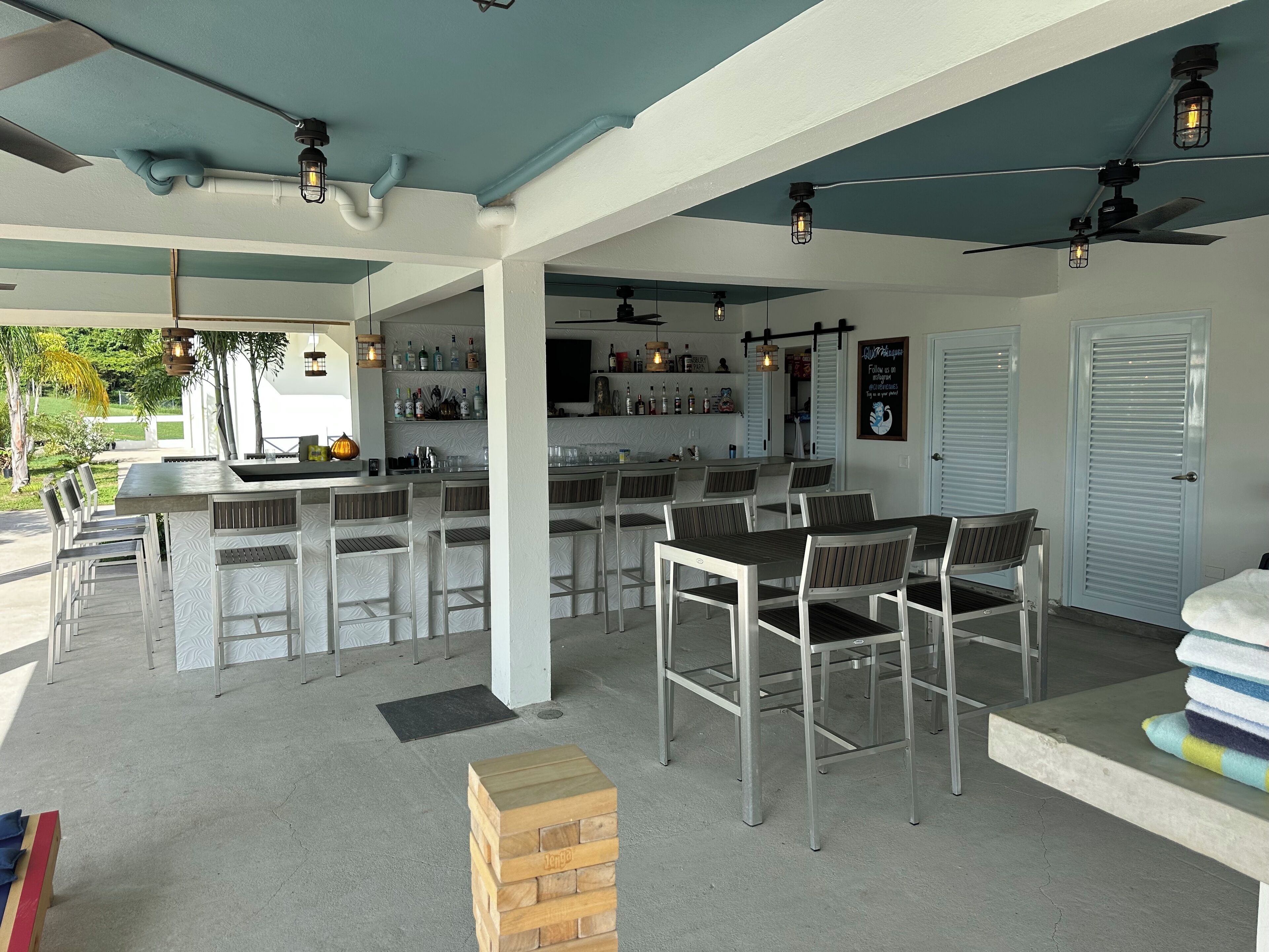 Een terras met een bar, verschillende zithoeken en een stapel handdoeken op een tafel.