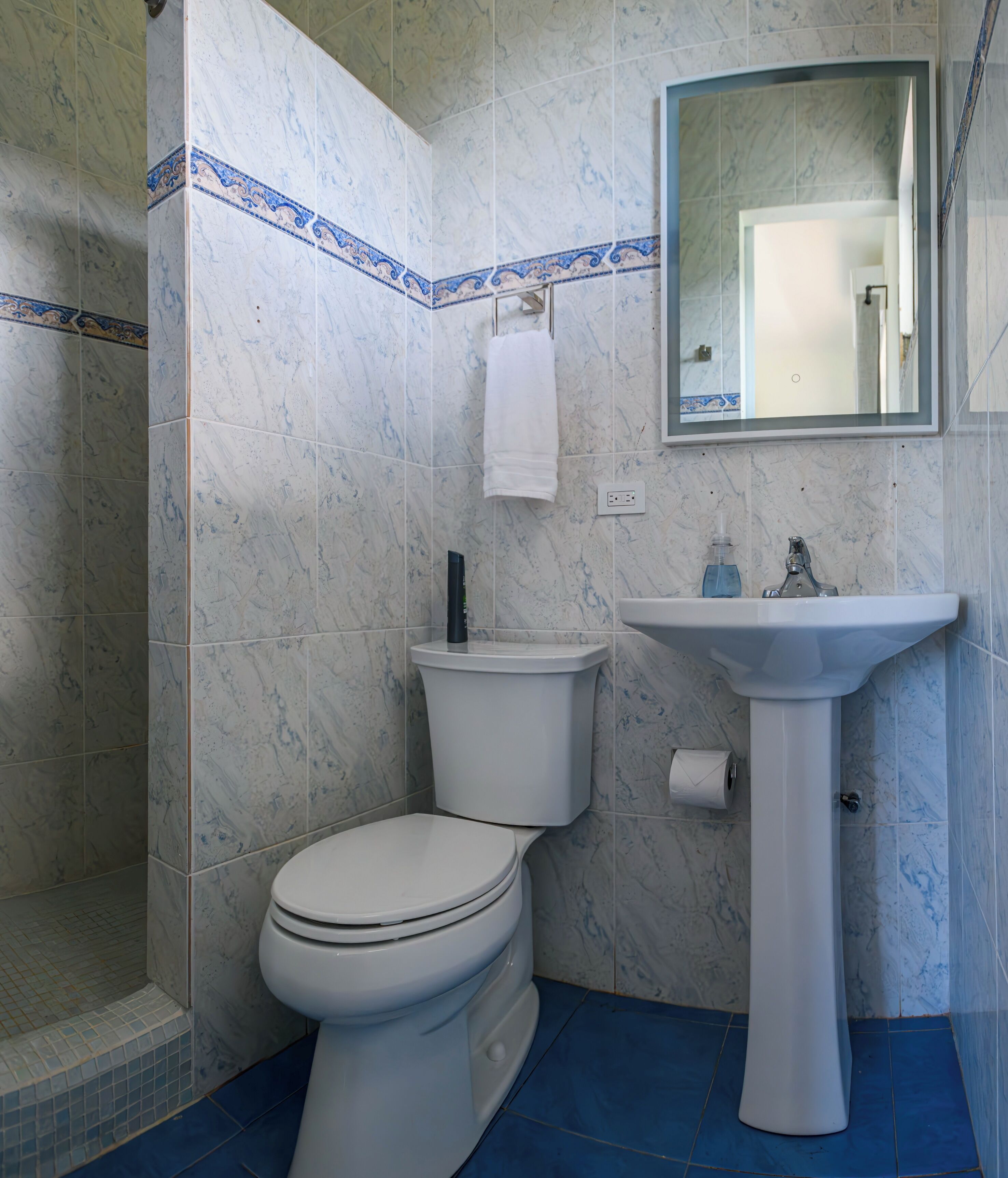 A bathroom with a toilet, sink, and shower.