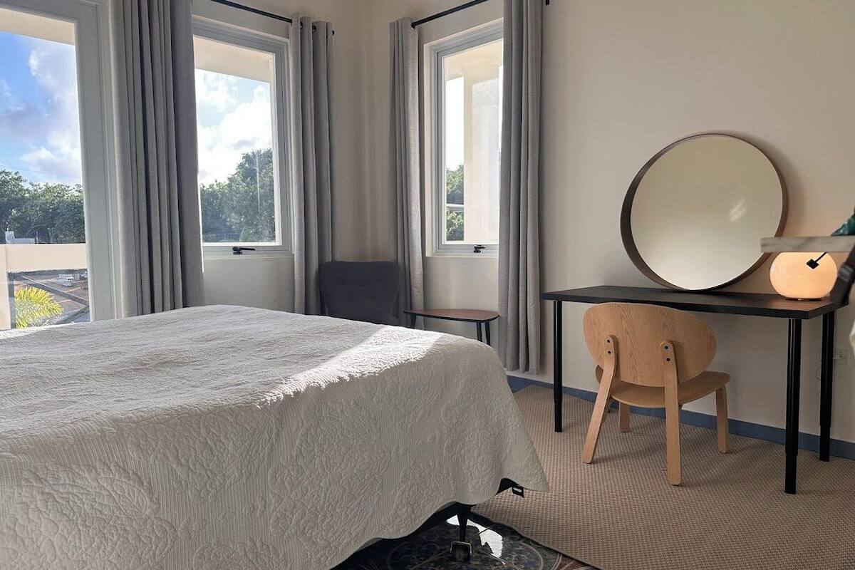 A hotel room with a bed, a desk with a mirror, and a chair.