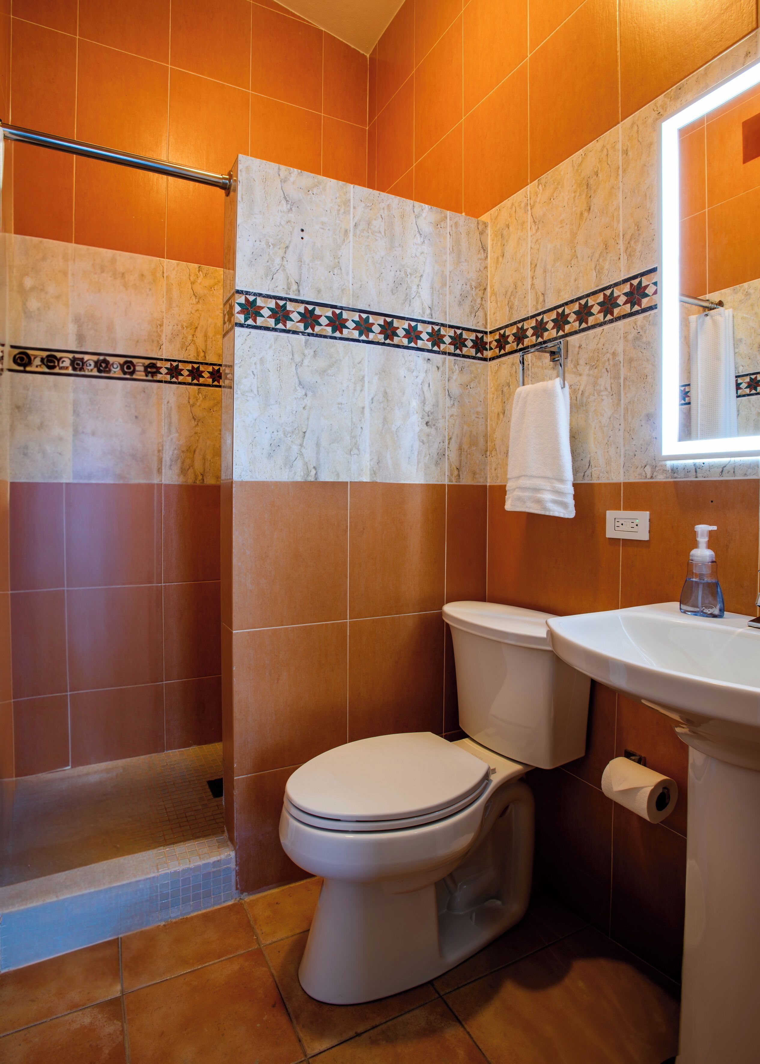 A bathroom with a toilet, sink, and shower area.