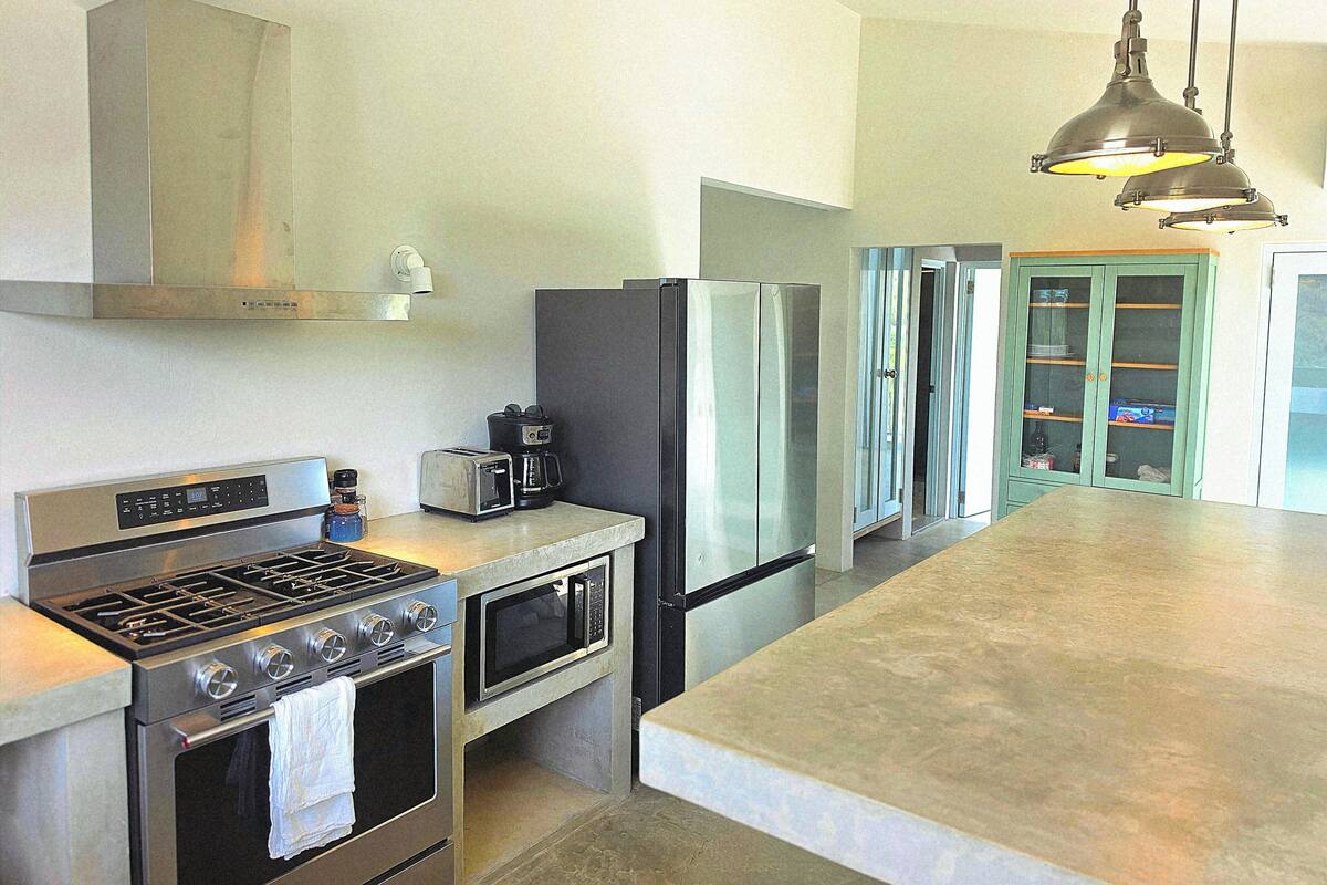 A modern kitchen with stainless steel appliances, a built-in oven, microwave, and a large island.