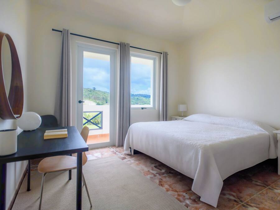 Une chambre d’hôtel équipée d’un lit, d’un bureau, d’une chaise, d’une lampe et offrant une vue sur l’extérieur.