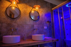Une salle de bain avec deux miroirs ronds, un meuble-lavabo en bois et une cabine de douche en verre.