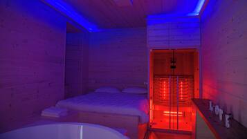 A wooden cabin room with a bed, a bathtub, and a sauna area.