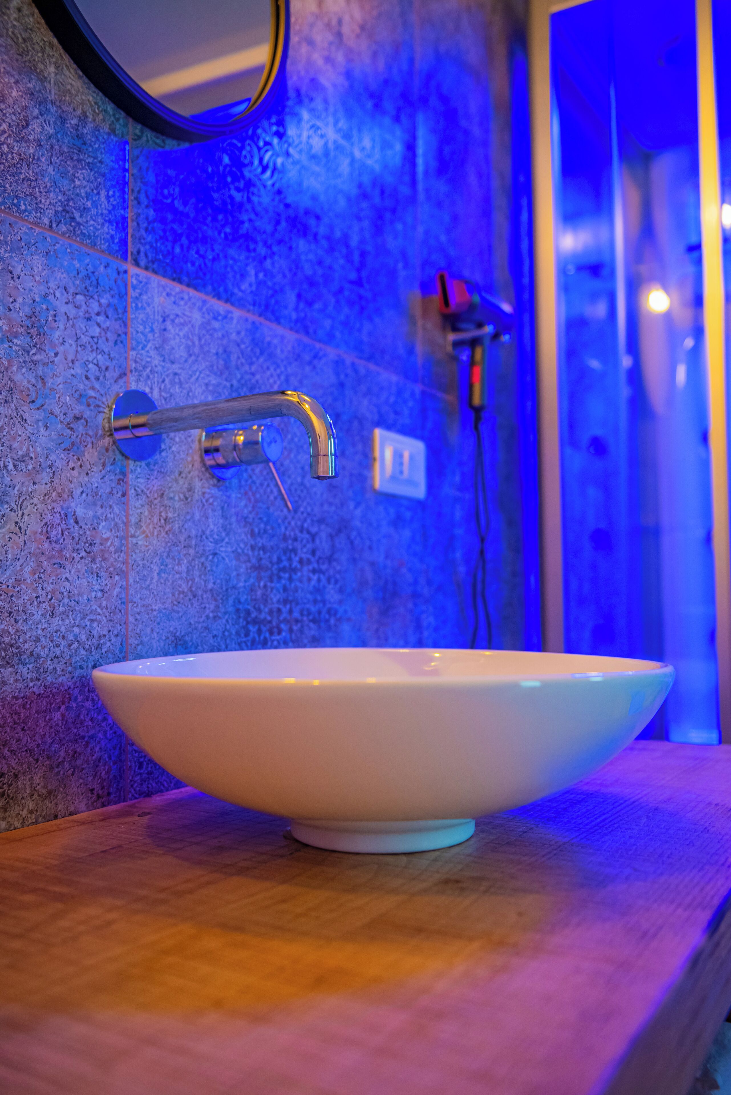A bathroom with a white sink, a mirror, and a blue-tiled wall.