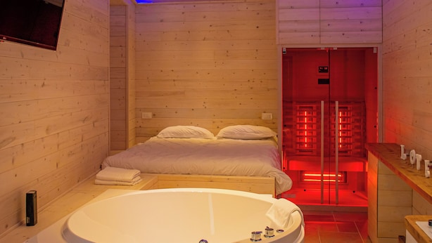 Una cabaña de madera con una bañera grande, una sauna y un techo de madera con iluminación empotrada.