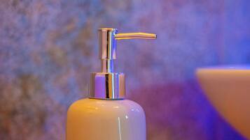 A white pump bottle on a wooden surface with a textured wall in the background.