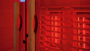Una habitación con sistema de ventilación iluminado en rojo, termostato digital y marco de puerta de madera.