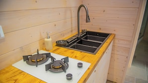 Una cocina compacta con estufa a gas, un lavamanos y armarios de madera.