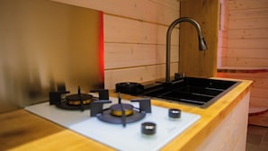 Una cocina con encimera de madera, estufa a gas, lavabo y grifo.