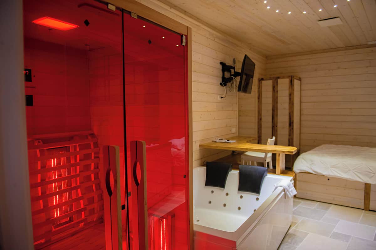 Quarto com sauna vermelha, cama de madeira e uma pequena mesa de madeira.