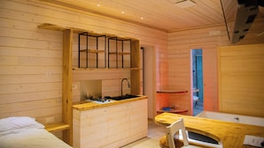 Una cabaña pequeña con kitchenette, una cama individual y un baño compacto.