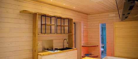 A compact cabin with a kitchenette, a single bed, and a small bathroom.
