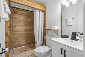 Une salle de bain équipée d’une douche, de toilettes, d’un lavabo et d’une fenêtre à cadre en bois.