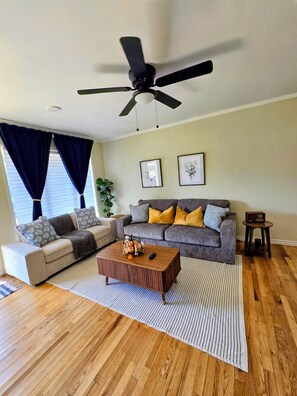 A living room with a ceiling fan, two sofas, a coffee table, and a side table.