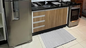 A modern kitchen with wooden cabinets, stainless steel appliances, and a black countertop. - Apartamento Refugio das Ondas - Piscina (Palhoça)